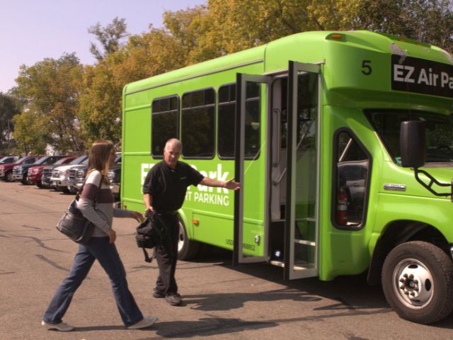 bus drive escorted a female travler onto a green airport shuttle bus